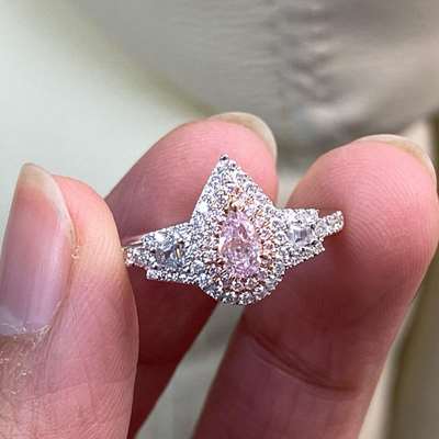 0.27ct GIA Certified Natural Light Pink Diamond, featuring SI2 clarity and a beautiful Pear shape. Accompanied by a pair of 0.07ct Trapezoid shoulder stones, this stunning diamond is set in a gorgeous halo setting.