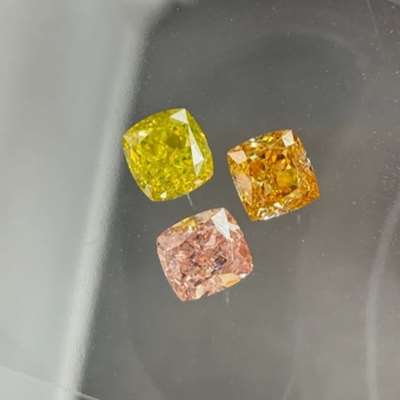  A 0.29ct GIA certified natural Vivid Greenish Yellow VS2, a 0.27ct GIA certified natural Fancy Orangy Pink VS2, and a 0.23ct GIA certified natural Fancy Intense Orange Yellow SI1, all in cushion cuts